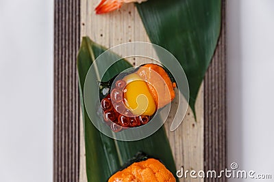 Sushi Set Close-up on Quail Egg Yolk Served on Leaf on Stone Plate. Stock Photo