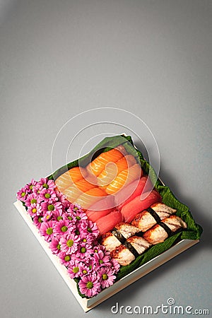 Sushi set with flowers in gift box on grey background. Creative chocolate candy box. Date, Valentines Day, Mother`s day Stock Photo