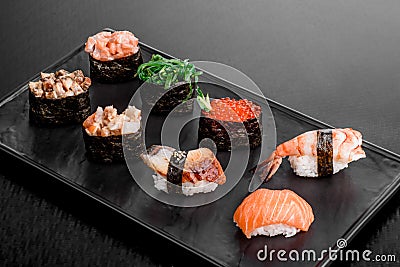 Gunkan and sushi set with salmon, eel, shrimp, chukka and chicken on a black plate on a dark background. . close up. Stock Photo