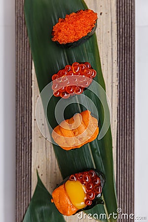 Sushi Set Include Tobiko, Ikura, Sea Urchin and Ikura, Urchin and Quail Egg Yolk Served on Leaf on Stone Plate Stock Photo
