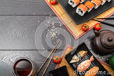 Sushi set sashimi and sushi rolls and tomatoes served on dark background Stock Photo