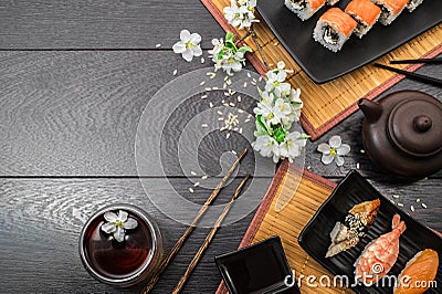Sushi set sashimi and sushi rolls and white flowers on dark background Stock Photo
