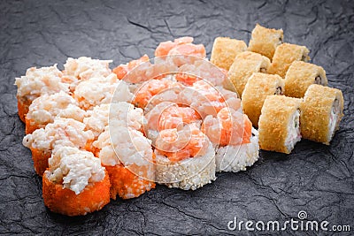 Sushi set served on dark background. Baked maki roll, Philadelphia maki, tempura maki with salmon, cream cheese, avocado and prawn Stock Photo