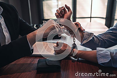 Suspect with handcuffs being interviewed in interrogation room by Police officer, Criminal law concept Stock Photo