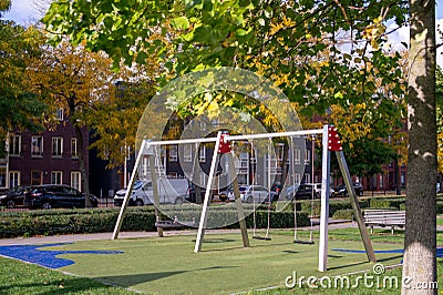 Suspended modern swing on the playground. Soft lawn covering Stock Photo