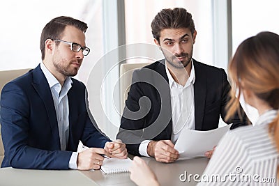 Suspicious recruiters doubting female candidate at interview Stock Photo