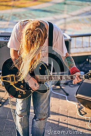 Rock musician playing guitar at outdoor heavy metal grunge festival, strum guitar, rock performance Editorial Stock Photo