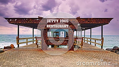 Swakopmund, Namibia - Nov 25, 2015: Rusty steel entrance to Jetty 1905 Restaurant and pier at coast of Swakopmund. Dark Editorial Stock Photo