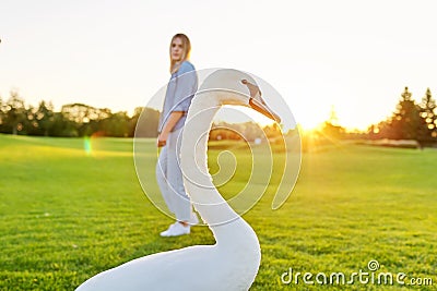 With swan and young woman, teenager together with swan on green lawn Stock Photo