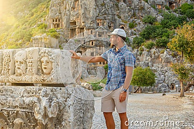 Swarthy caucasian european guy in plaid shirt in a cap looks at the sunset the ancient unique landmarks Turkey, Antalya Demre, Stock Photo