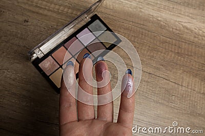 Swatches of palette eyeshadows on a woman`s hand. Wood backgroun Stock Photo