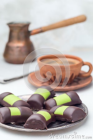 Swedish sweets punsch rolls or punschrullar, covered with green marzipan, on metall plate, served with coffee, vertical Stock Photo
