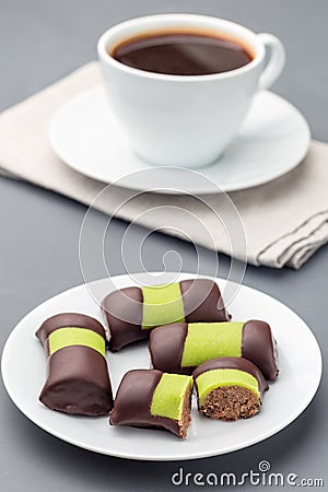 Swedish sweets punsch rolls or punschrullar, covered with green marzipan, on white plate, served with coffee, vertical Stock Photo