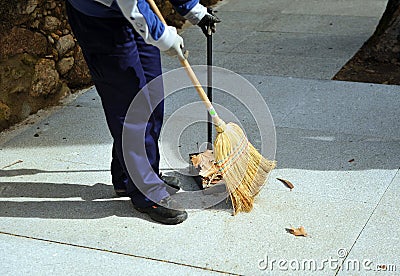 Sweeper in the street sweeping up with her broom Stock Photo