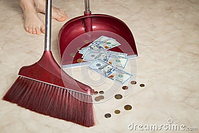 Sweeping dollars and coins into a dustpan at home from the floor, business and finance, littering with money Stock Photo