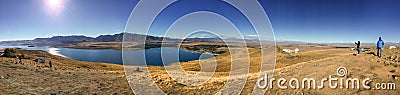 Sweeping panoramic views of the spectacular golden Mackenzie Basin from the top of Mt John including Lake Tekapo with people in Editorial Stock Photo