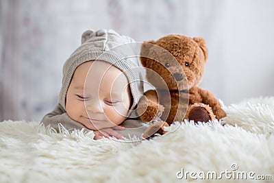 Sweet baby boy in bear overall, sleeping in bed with teddy bear Stock Photo