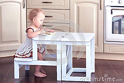 Sweet Baby Eats by herself at a Small Folding Ladder-Table Chair. Stock Photo