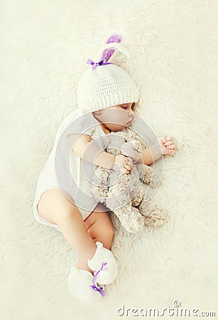 Sweet baby sleeping with teddy bear toy on white soft bed home Stock Photo