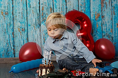 Sweet blond toddler child, boy, playing on his birhtday with toys and little chocolate cake Stock Photo