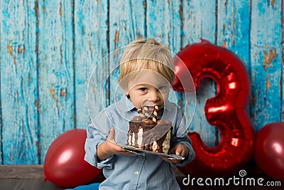 Sweet blond toddler child, boy, playing on his birhtday with toys and little chocolate cake Stock Photo