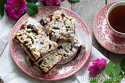 Sweet cake with cherry rose arenas and streusel on a wooden background. Rustic style Stock Photo