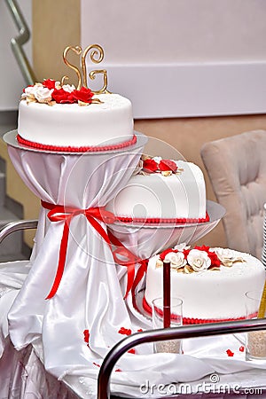 Sweet cakes in the form of red roses decorate the wedding cake with more decorative twigs of white cream Stock Photo