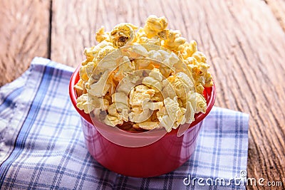 Sweet caramel popcorn in a bowl on blue cotton napkin against wooden background Stock Photo