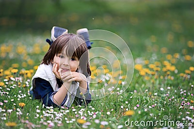 Sweet child, boy, gathering dandelions and daisy flowers Stock Photo