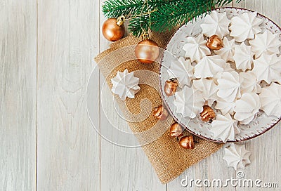 Sweet christmas background with airy meringues ,fir branch,golden acorns and balls on the plate.Rough sackcloth Stock Photo