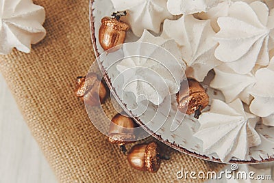 Sweet christmas background with airy meringues,golden acorns on the plate. Stock Photo