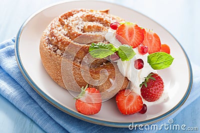 Sweet cinnamon roll with cream and strawberry for breakfast Stock Photo