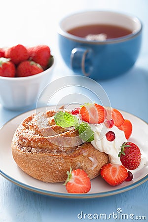 Sweet cinnamon roll with cream and strawberry for breakfast Stock Photo