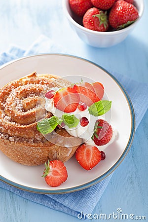 Sweet cinnamon roll with cream and strawberry for breakfast Stock Photo