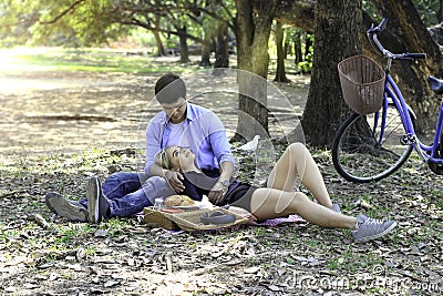 Sweet couple relaxing on picnic in park woman lay down on her boyfriend lap young beautiful lover spending time together and Stock Photo