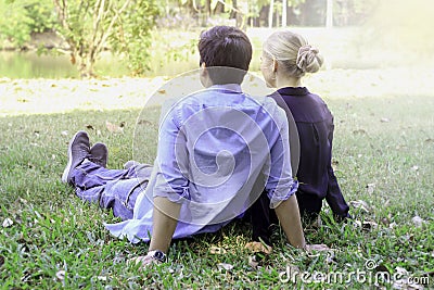 Sweet couple sitting on green grass in park young beautiful lover spending time together and having romantic moment in summer Stock Photo