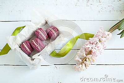 Sweet crimson french macaroons with box and hyacinth on light dyed wooden background Stock Photo