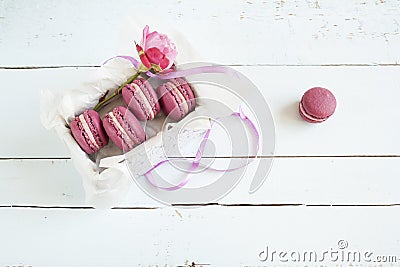 Sweet crimson french macaroons and rose with box on light dyed wooden background Stock Photo