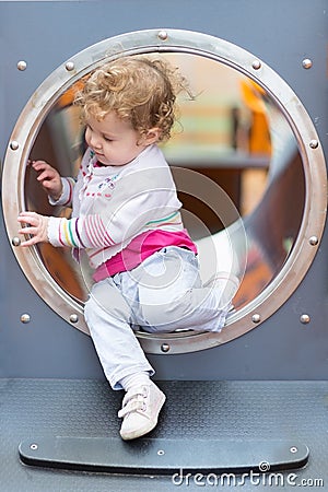 Sweet curly baby girl sliding on a playground Stock Photo