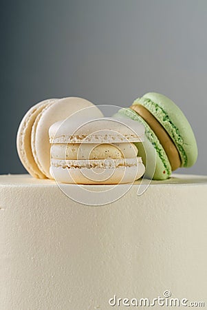 Sweet, delicious macarons are laid out as a cake topper. Cake side view, stands on the table. Stock Photo