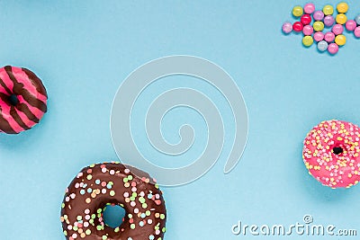 Sweet donuts with colorful candies on the blue background. Stock Photo