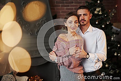Sweet elegant lovers. Nice couple celebrating new year in front of Christmas tree Stock Photo