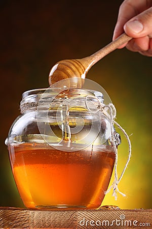 Sweet honey pouring from drizzler into the pot. Stock Photo