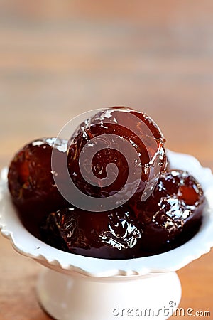 Sweet Jujube or Chinese red date in syrup in white Thai style cup on wood table and space for write wording Stock Photo