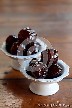 Sweet Jujube or Chinese red date in syrup in white Thai style cup on wood table and space for write wording Stock Photo
