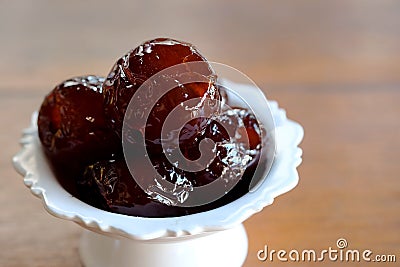 Sweet Jujube or Chinese red date in syrup in white Thai style cup on wood table and space for write wording Stock Photo