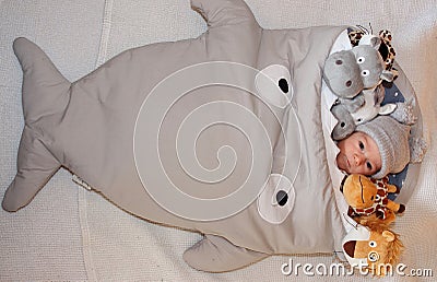 Sweet little baby lying on the bed surrounded of cute safari stuffed animals Stock Photo