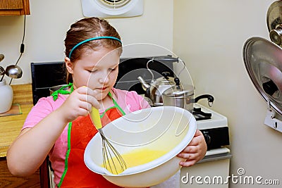 Sweet little cute girl is learning how to make a cake, in the home kitchenlearns to cook a meal in the kitchen Stock Photo