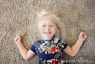 Sweet Little Girl Child in Flower Dress Laying on Carpet, Smilin Stock Photo