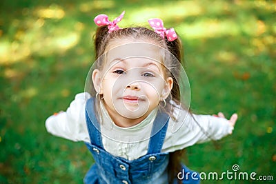 Sweet little girl outdoors with curly hair in two long tails, closeup portret. Stock Photo